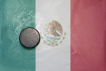 old hockey puck is on the ice with national flag of mexico .