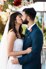 Happy couple, wedding and kiss with love or hug for affection, marriage or embrace at outdoor...