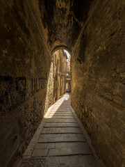 Wąska uliczka miedzy kamiennymi kamienicami na starym mieście w miasteczku Perugia, Toskania,...