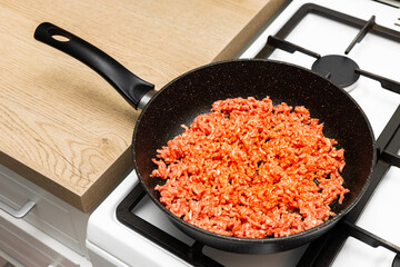 fresh minced meat lies on a frying pan.