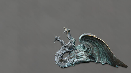 Old bronze figurine of a dragon with wings on a gray background
