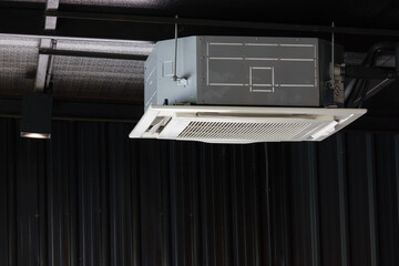 air condition hanging from ceiling. cassette type air conditioner in dark room.