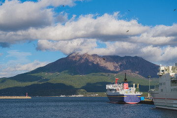 Japanese cargo, passenger and car ferry with Sakurajima volcano and picturesque coastal scenery in...