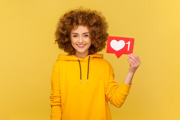 Cheerful carefree woman with Afro hairstyle holding Heart Like icon of social media, notification...