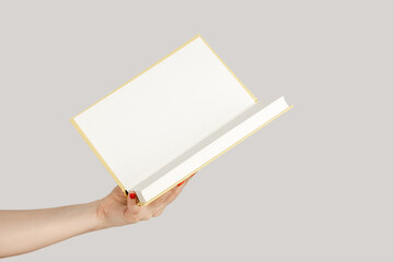 Closeup of woman hand showing open paper organizer with empty pages, copy space for promotion....