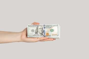 Closeup of woman hand showing dollar banknotes, earning money, salary, jackpot. Indoor studio shot...