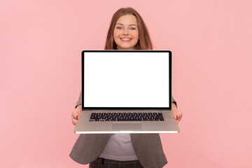 Portrait of smiling joyful woman with brown hair holding laptop with empty display, copy space for...