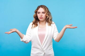 Portrait of puzzled confused blond woman with wavy hair standing shrugging shoulders not sure looks...