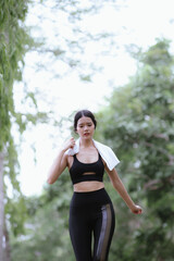 Beautiful Asian female runner doing morning exercise outdoors in city park. smile happily Exercise for good health