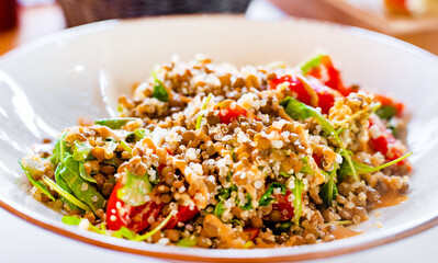 Quinoa with tomatoes and herbs, topped with sauce.