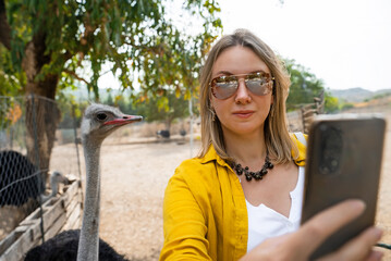 A girl takes a selfie with an ostrich.