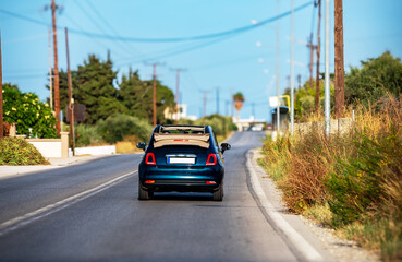 A convertible car is driving along the road. Back view.