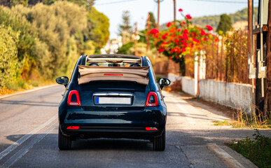 Fototapeta premium A convertible car is driving along the road. Back view.