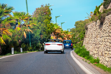 White cabrio car is driving along the road. Back view.