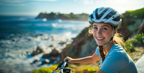 A young woman on a bicycle with a helmet smiling at the camera, blurred background showing coastal...