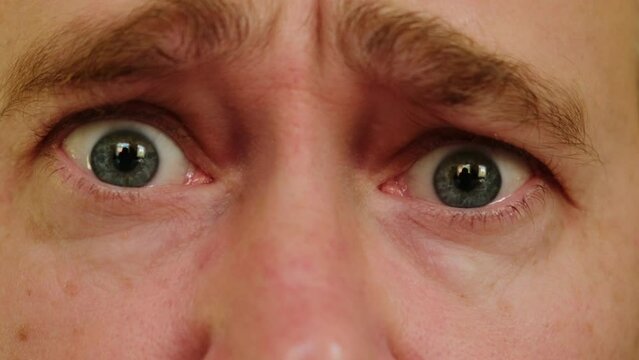 Close-up gray eyes of unhappy pleading man. A male person looking at camera feeling depression and upset.