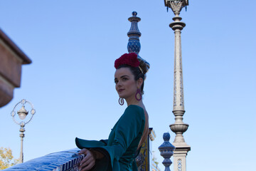 Beautiful young woman with typical green frilly dress and dancing flamenco in plaza de espana in...
