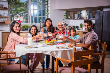Indian family having lunch at home on dining table with grandparents, parents and kids