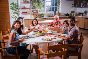 Indian family having lunch at home on dining table with grandparents, parents and kids