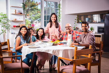 Indian family having lunch at home on dining table with grandparents, parents and kids