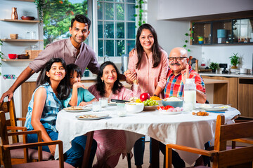 Happy Indian asian family having lunch at home and posing for photo