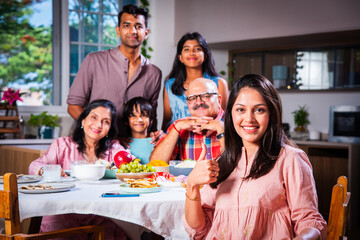 Happy Indian asian family having lunch at home and posing for photo