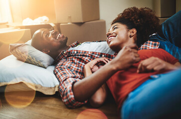 Black couple, relax and smile on floor of new house with bonding, support and break from moving....