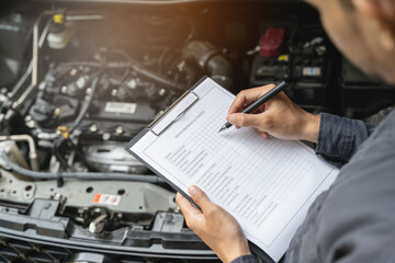 Auto check up and car service shop concept. Mechanic writing job checklist to clipboard to estimate repair quotation to client at workshop garage. - Powered by Adobe