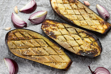 Baked eggplant with onions, garlic and sesame seeds on paper