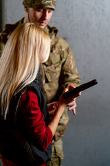 close up in a professional shooting range military man tells and shows a girl the correct stance...
