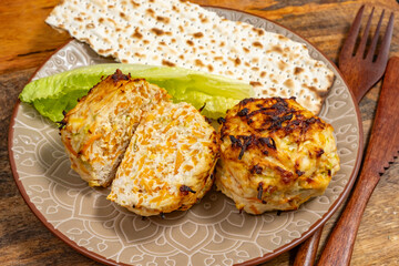 Chicken Vegetables Cutlets served with lettuce leaf, wooden cutlery, matzah piece on ceramic plate for Jewish holiday Pesach..