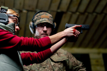 low shot in a professional shooting range military man tells and shows a girl the correct stance...
