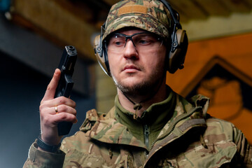 close-up at a professional shooting range military man stands in ammunition and holds a pistol