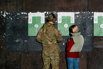 a professional shooting range military trainer and a girl check the target for hits