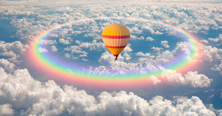 Hot air balloon flying over the clouds with rainbow halo
