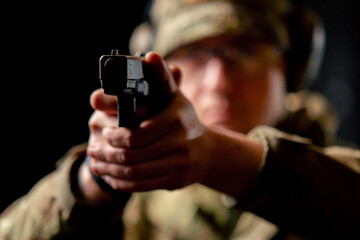 close-up at a professional shooting range a military trainer in ammunition takes aim with a pistol