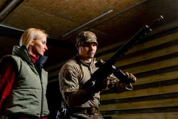 At a professional shooting range military trainer tells a girl how to properly handle NATO weapons