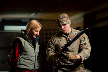 At a professional shooting range military trainer tells a girl how to properly handle NATO weapons