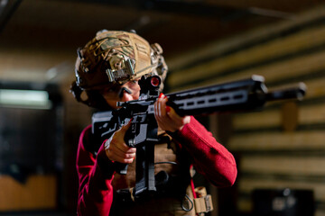 In a professional shooting range young girl in tactical ammunition is preparing to shoot