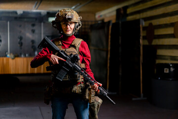 at a professional shooting range girl in tactical ammunition stands with a NATO rifle