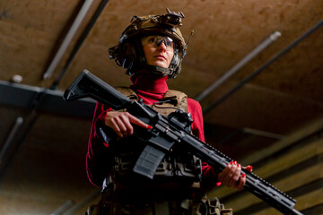 low shot at a professional shooting range girl in tactical ammunition stands with a NATO rifle