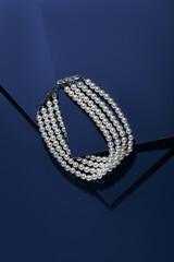 Pearl necklace on a blue background. Natural pearls. Expensive and beautiful jewelry. Top view. 