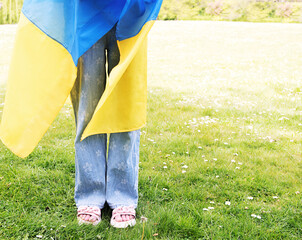 A girl is standing in a clearing. The child is wrapped in the flag of Ukraine. Pray for Ukraine....