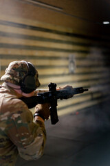 In a professional shooting range military man in ammunition makes a shot from a NATO rifle
