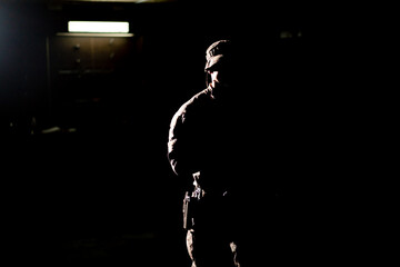 military man on tactical strategy stands in the dark contrasting light back light silhouette