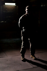 military man on tactical strategy stands in the dark contrasting light back light silhouette