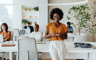 Successful afro-haired woman in modern office using smartphone - Powered by Adobe