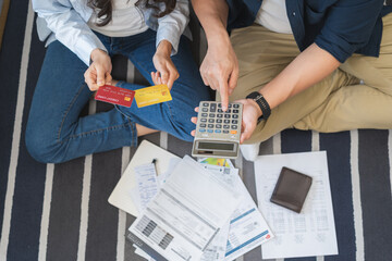 Fototapeta premium Stressed financial owe asian young couple love sitting stressed and confused hand calculate expense from credit card, invoice no money to pay, mortgage or loan. Debt, bankrupt or bankruptcy people.