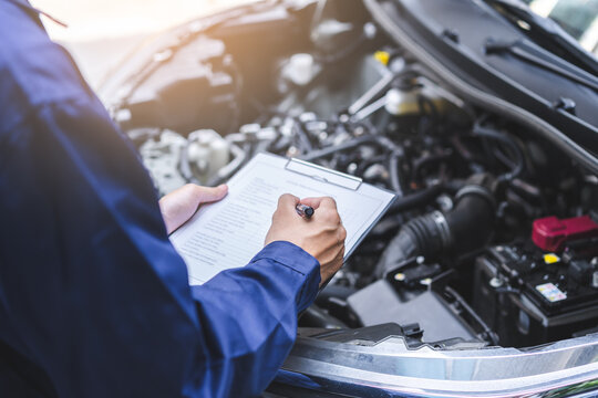 Auto check, car service shop concept. Automobile repairman writing job checklist on clipboard, mechanic checking engine to estimate repair machine, inspecting maintenance by engineer at vehicle garage