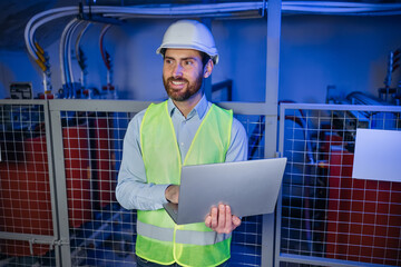 Professional Industry Engineer or Worker Wearing Safety Uniform and Hard Hat Uses Laptop Computer. Smiling Specialist Standing in technical room